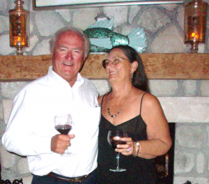 Rick and Charlene holding glasses of wine in front of the fireplace at Fowl Cay Resort
