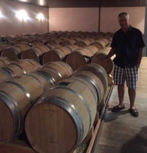 Joe standing with wine barrels at Chateau du Payre