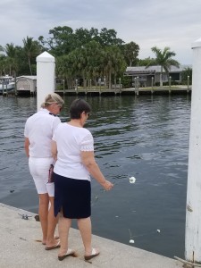 Past Commodore Deborah Ross and Charlene tossing a carnation into the water in remembrance of Rick