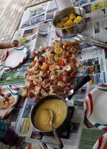 Shrimp Boil ingredients on newspaper with corn on the cob and cheese grits
