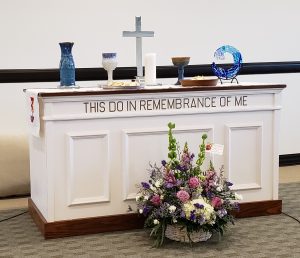 Ordination Table with Objects on Top and flowers on floor in front