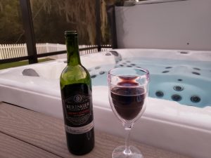 Wine bottle and glass sitting on edge of hot tub