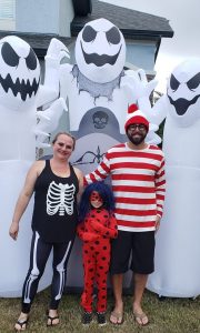 Family in costume standing in front of large blow-up ghosts