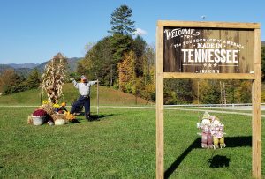 Welcome to Tennessee Sign. Scarecrow with pumpkin head and cornstalks.