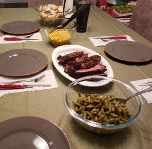 Dinner Table with potatoes, mac and cheese, prime rib and green beans surrounded by place settings