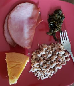 Dinner plate with ham, greens, black-eyed peas in rice and corn bread