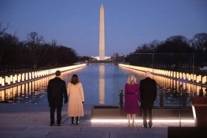 4 people standing in front of the reflecting pool in front of the Washington Monument lined with 400 lights in memorium