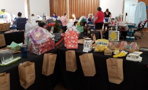 Tables with raffle items displayed and a brown paper bag in which to put a ticket