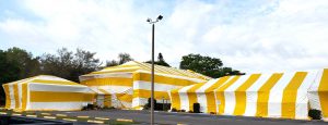 3 buildings covered with yellow and white striped tents