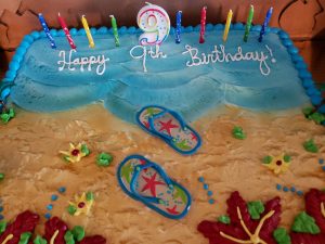 birthday cake and candles with a picture of a beach and flip flops