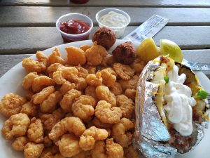 A plate filled with fried shrimp and a baked potato
