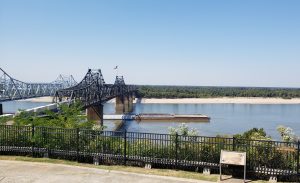A car bridge and a train bridge crossing the Mississippi River with a barge going underneath