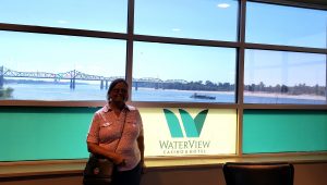 Jackie standing by a Waterview Casino sign with the Mississippi River in the background