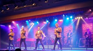 4 men in shiny gold jackets singing