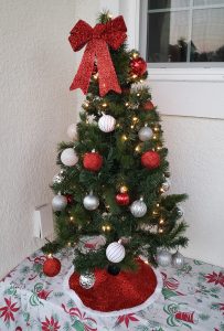 Small Christmas tree decorated with red, white and silver balls and a red bow on top