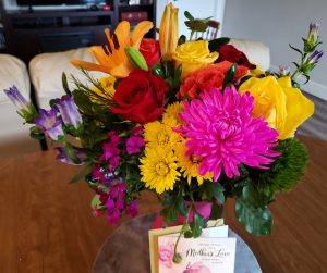 Multi-colored flowers with Mothers' Day card leaning against vase