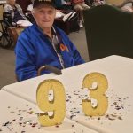 Tom Cambre sitting at table with gold numbers 93