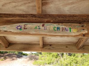Sign painted on driftwood that says Emma's Beach Hut
