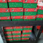 A cart stacked high with red and green shoeboxes