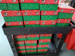 A cart stacked high with red and green shoeboxes
