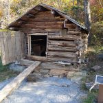 A small log henhouse with a ramp up to the door