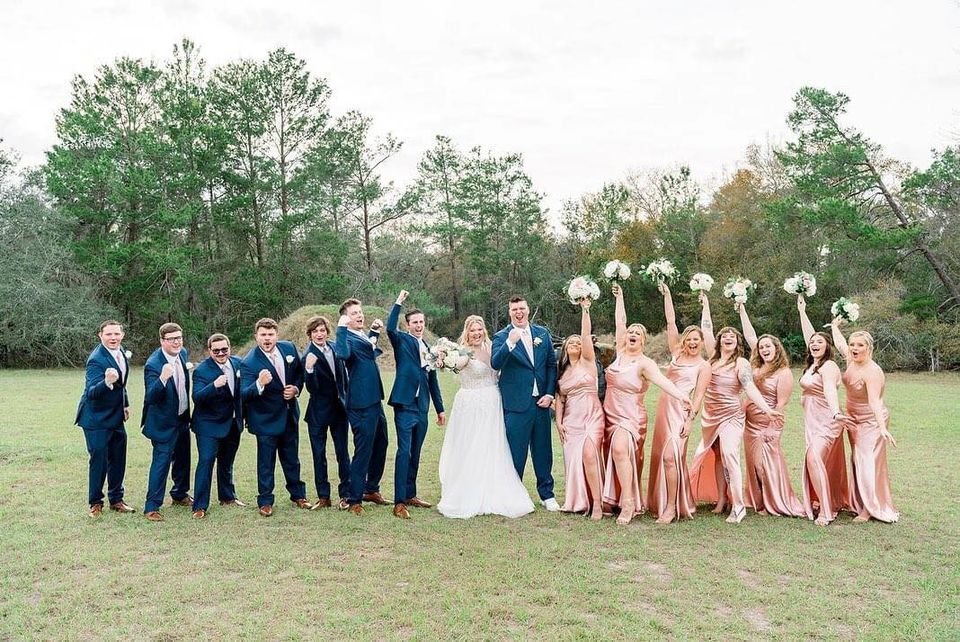 Men in blue and ladies in peach flank the bride and groom